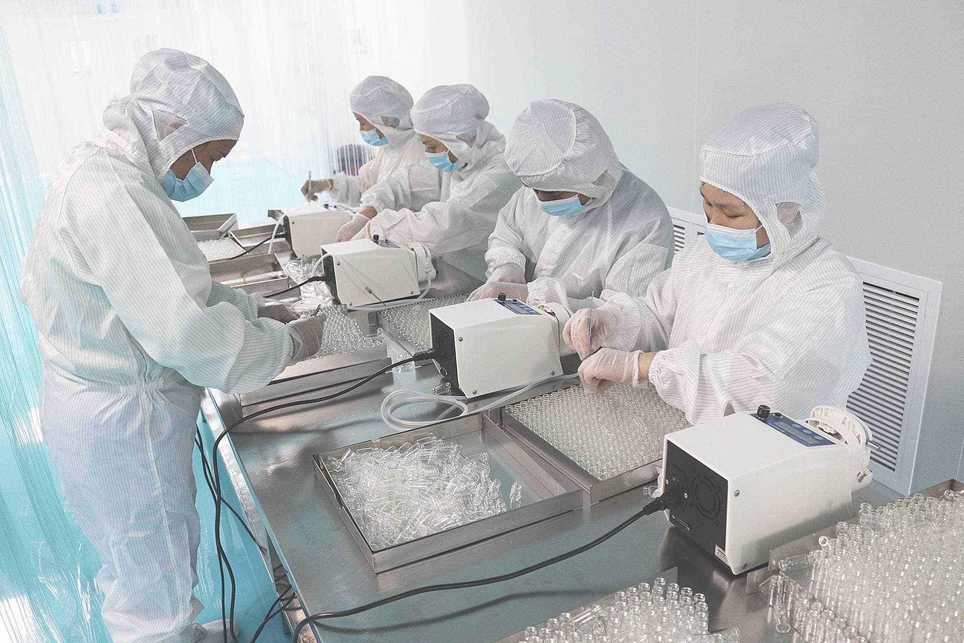 Cleanroom team inspecting vials on a production table